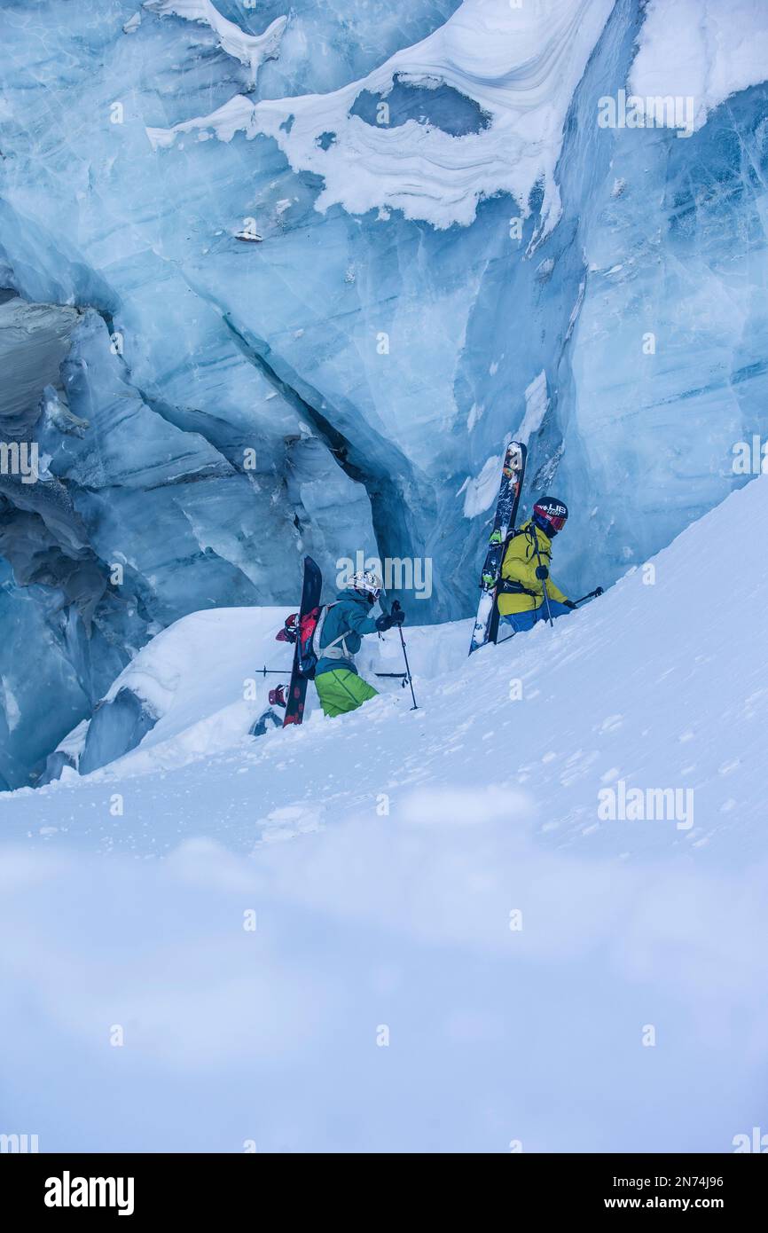 Due snowboarder professionisti e sciatori esplorano e sciano una grotta di ghiaccio sul ghiacciaio Pitztal, Pitztal, Tirolo, Austria Foto Stock