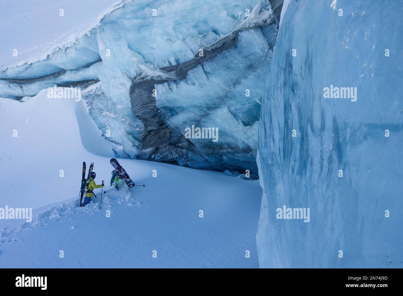 Due snowboarder professionisti e sciatori esplorano e sciano una grotta di ghiaccio sul ghiacciaio Pitztal, Pitztal, Tirolo, Austria Foto Stock