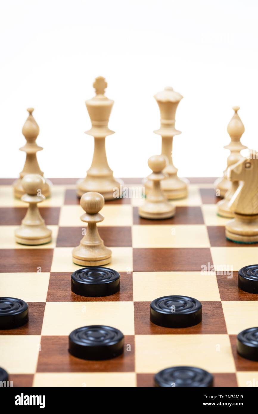 giocare con regole diverse sulla stessa tavola - pedine nere e figure bianche di scacchi su scacchiera di legno, tabellone con scacchi e pedine Foto Stock