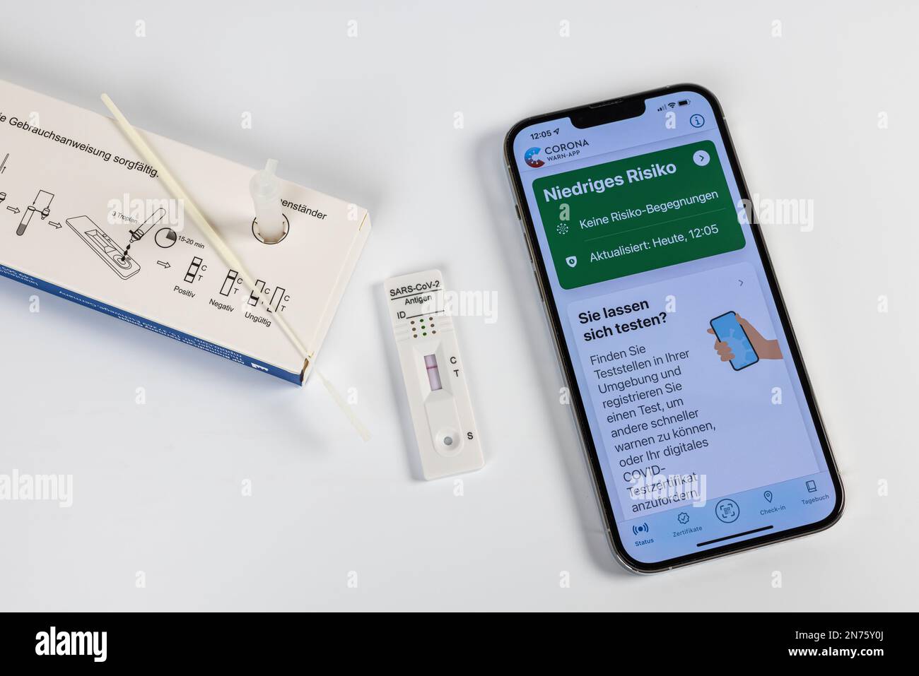 Confezione con istruzioni per l'uso, tampone, provetta di estrazione, soluzione di estrazione, cassetta per test antigeni Rapid SARS-COV-2 con risultato positivo, app di avviso per iPhone Corona, aperta, verde a basso rischio, fondo bianco, Foto Stock