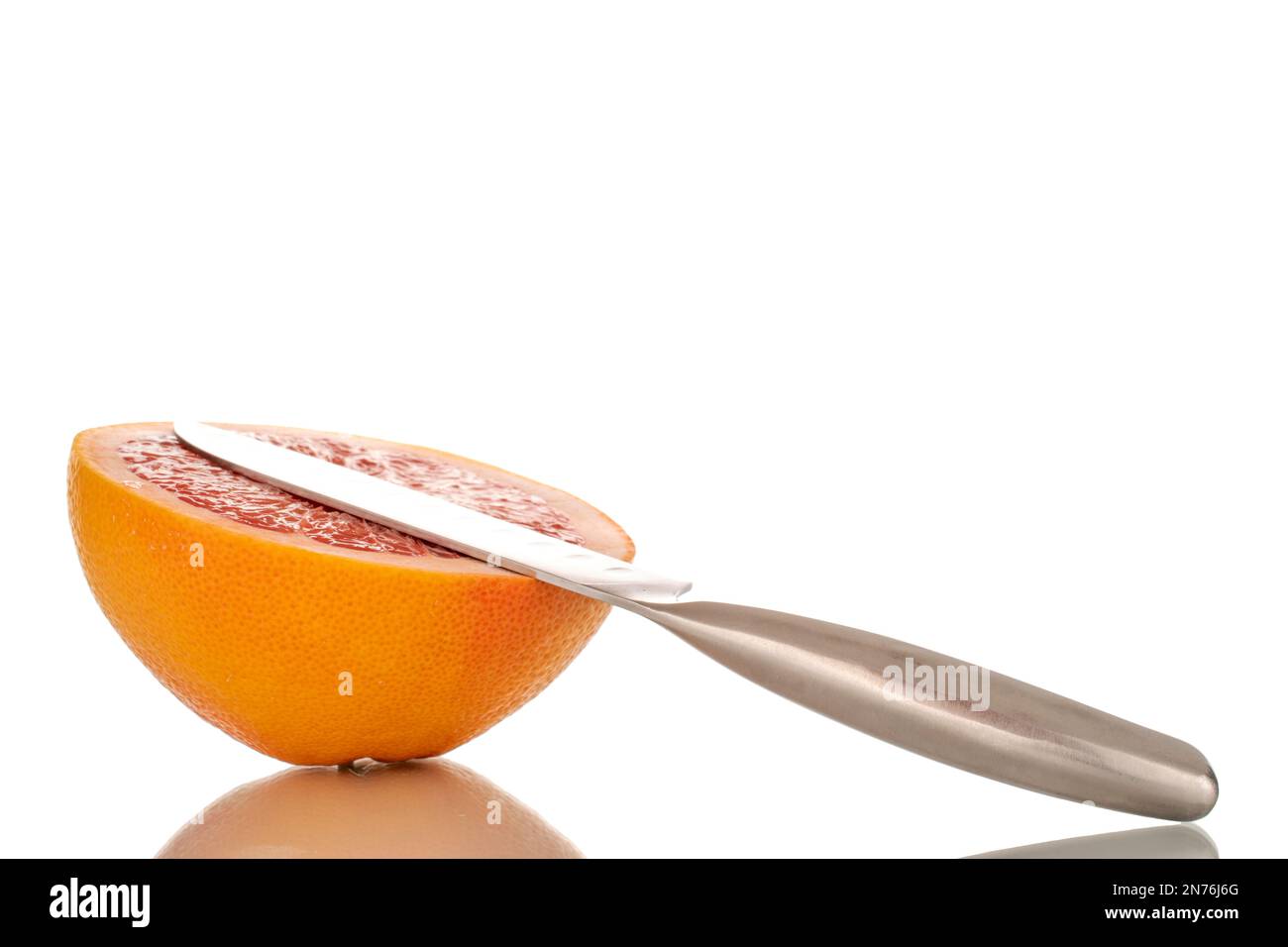 Metà di un pompelmo maturo con un coltello di metallo, macro, isolato su fondo bianco. Foto Stock