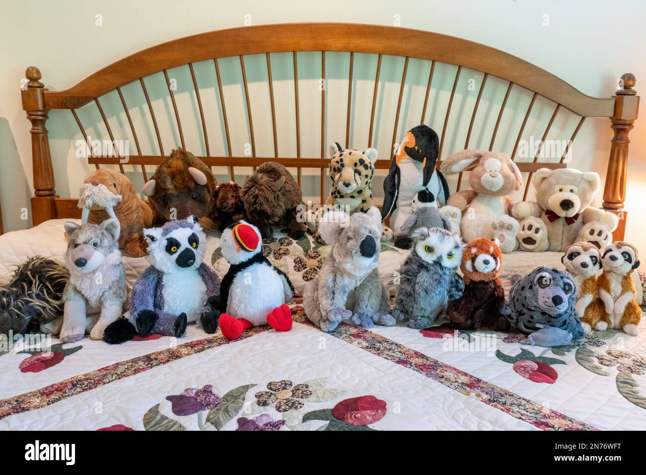 Assortimento di animali ripieni che riposano su un letto coperto di trapunta in una camera da letto Foto Stock