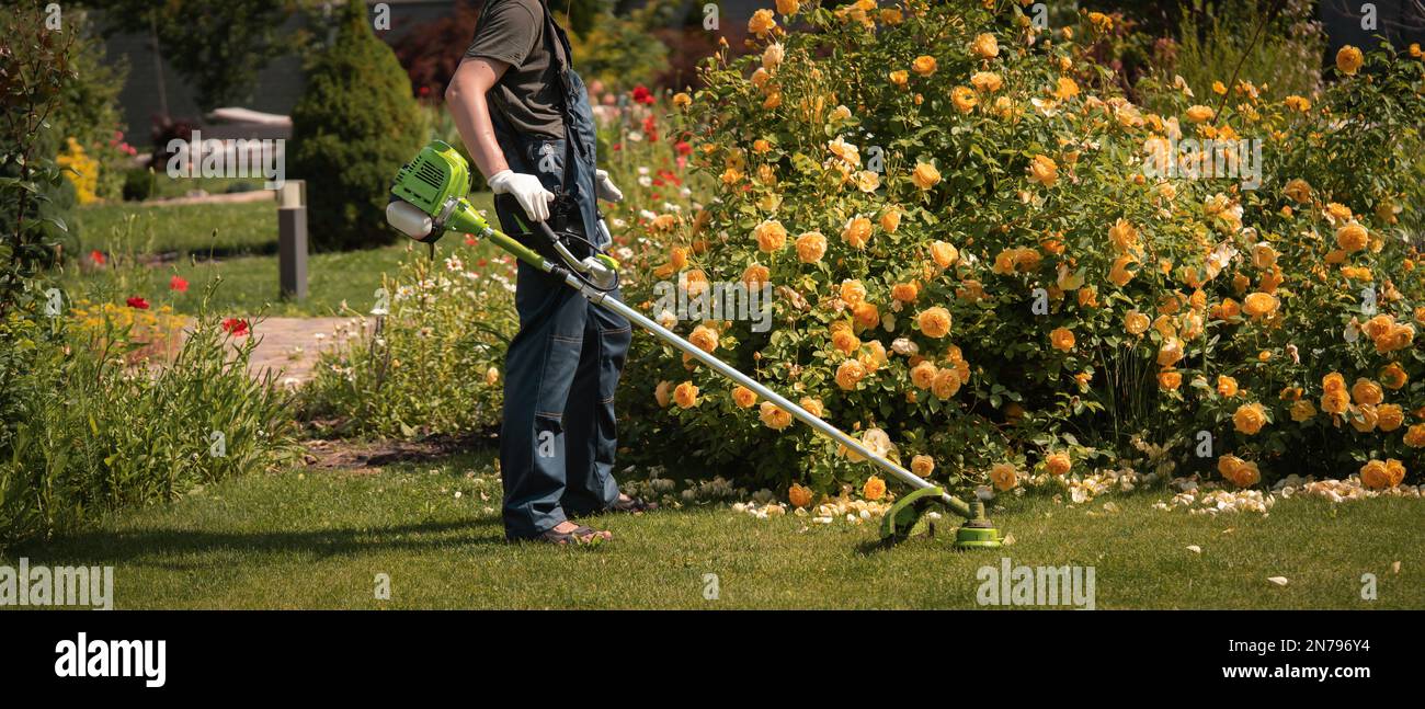 Un uomo con un rasaerba nel cortile Foto Stock