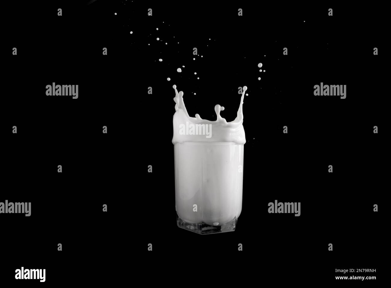 Gocce di latte in un bicchiere su sfondo nero. Foto Stock