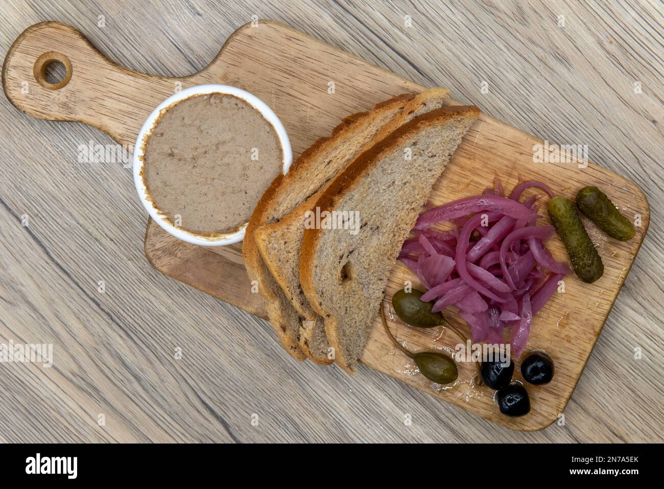 Vista dall'alto di un appetitoso antipasto con cornichon e capperi serviti su un tagliere di legno. Foto Stock