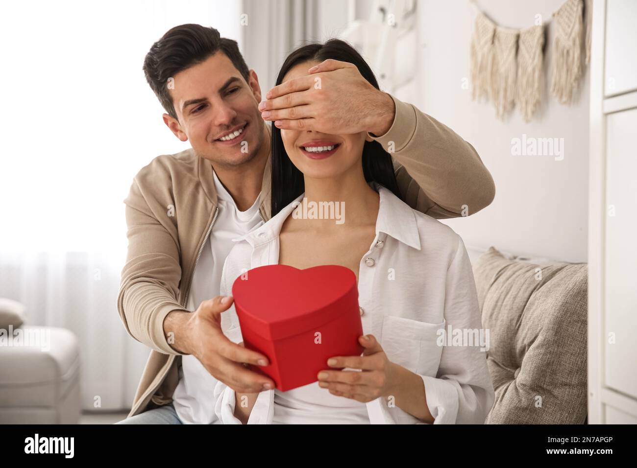 L'uomo presenta il dono alla sua amata donna a casa. Festa di San Valentino  Foto stock - Alamy