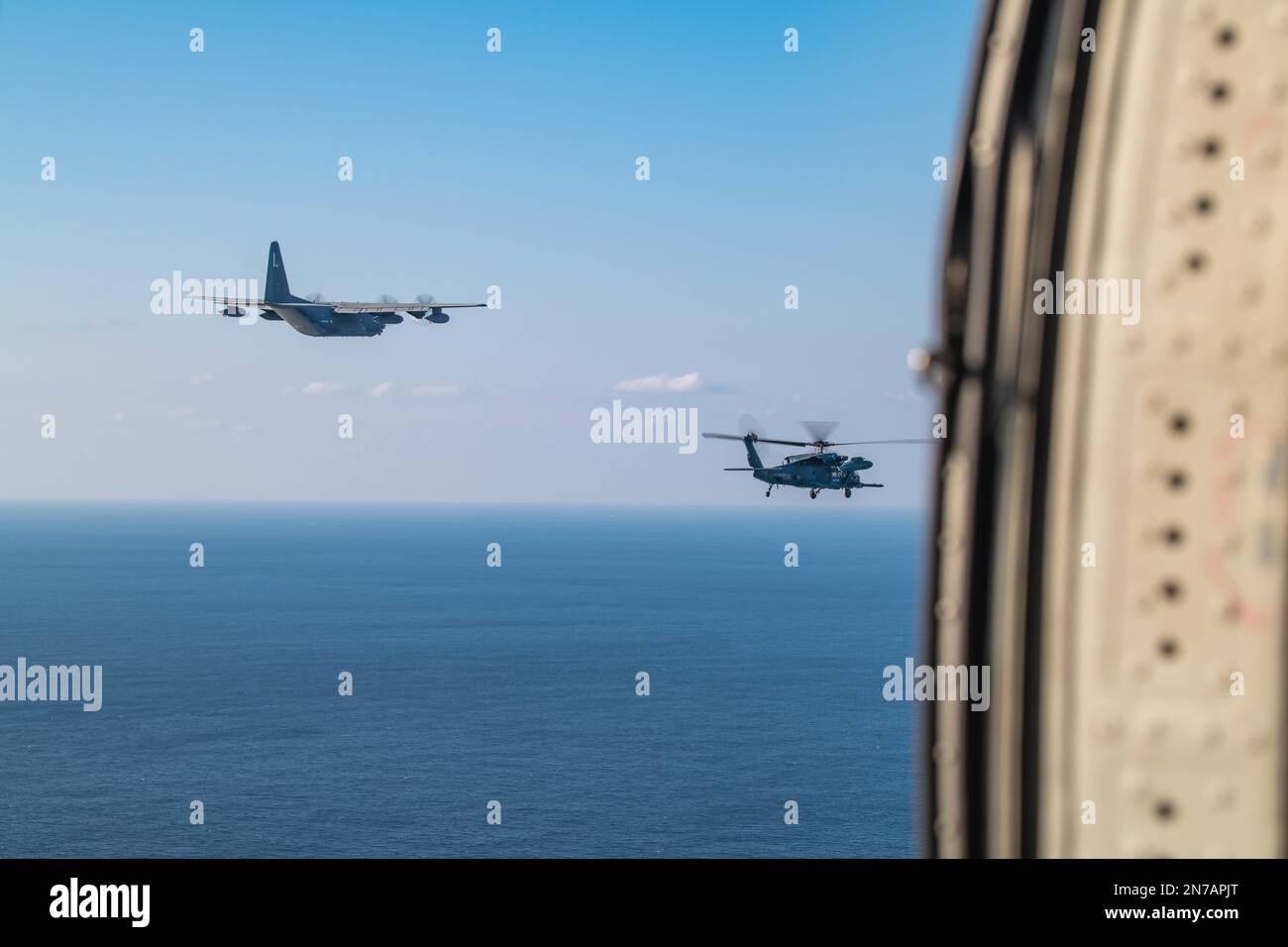 NEGLI STATI UNITI Air Force MC-130J Commando II, assegnato al 1st Special Operation Squadron vola a fianco di un elicottero giapponese Air Self-Defense Force UH-60J al largo della costa dell'isola di Ukibaru 19 gennaio 2023. L'esercitazione bilaterale di addestramento assicura la coerenza nella sicurezza attraverso Okinawa insieme alle forze giapponesi di autodifesa. (STATI UNITI Air Force foto di Airman 1st Class Alexis Redin) Foto Stock