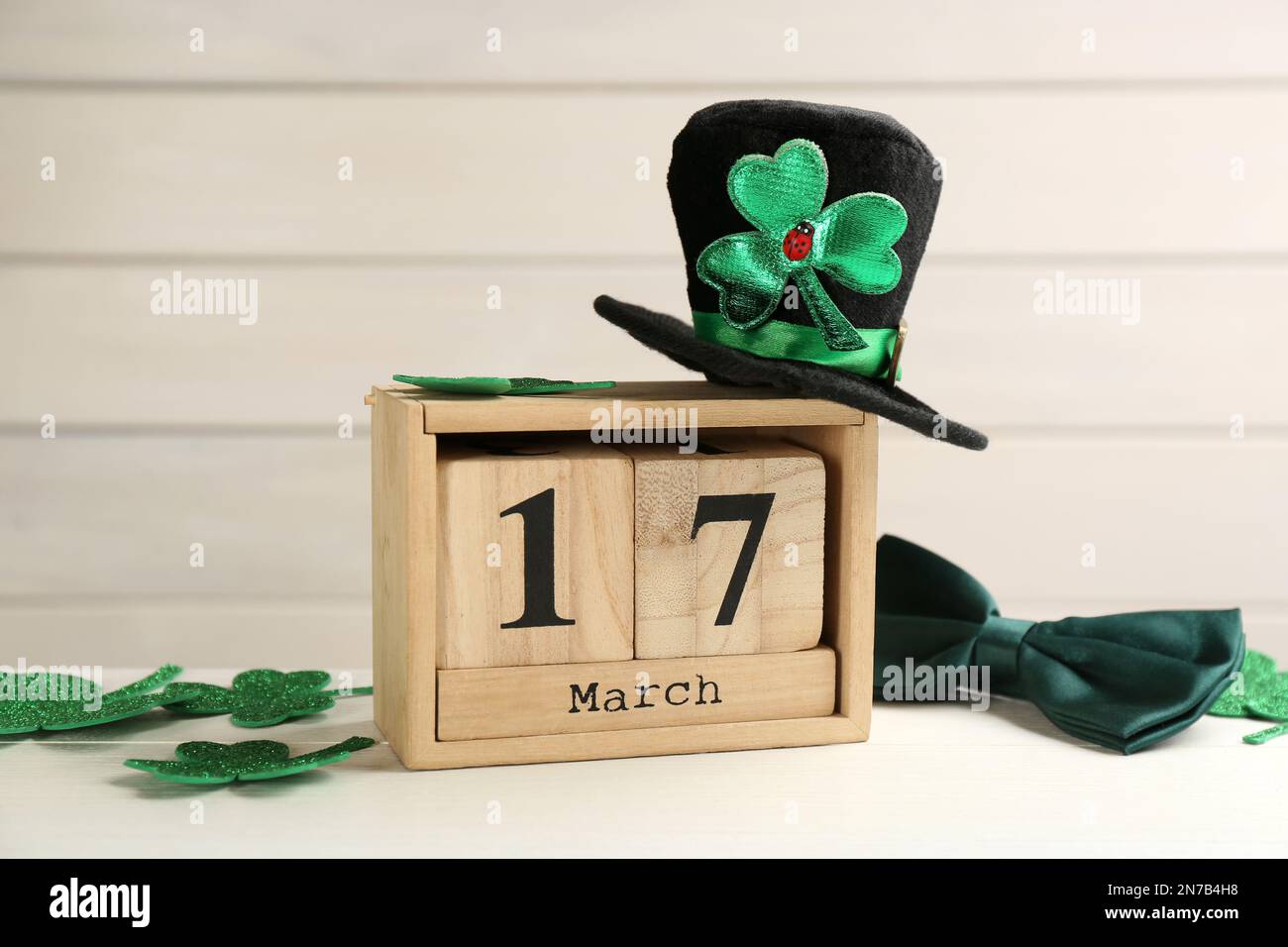 Composizione con cappello leprechaun e calendario a blocchi su tavolo di legno bianco. Festa di San Patrizio Foto Stock