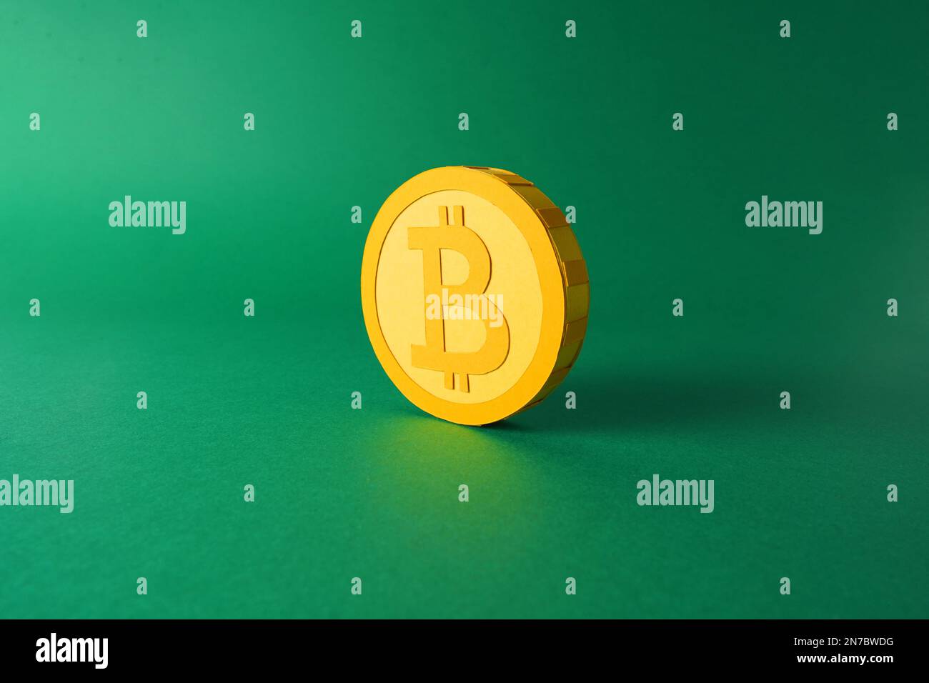 Modello di carta ritagliata di un gettone giallo da 3D bitcoin su sfondo minimalistico, cripto blockchain paperraft art su fondo piatto verde Foto Stock