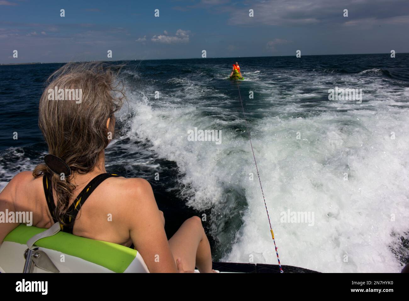 Donna guarda una persona su un'imbarcazione ad acqua trainata da una barca a motore. Foto Stock