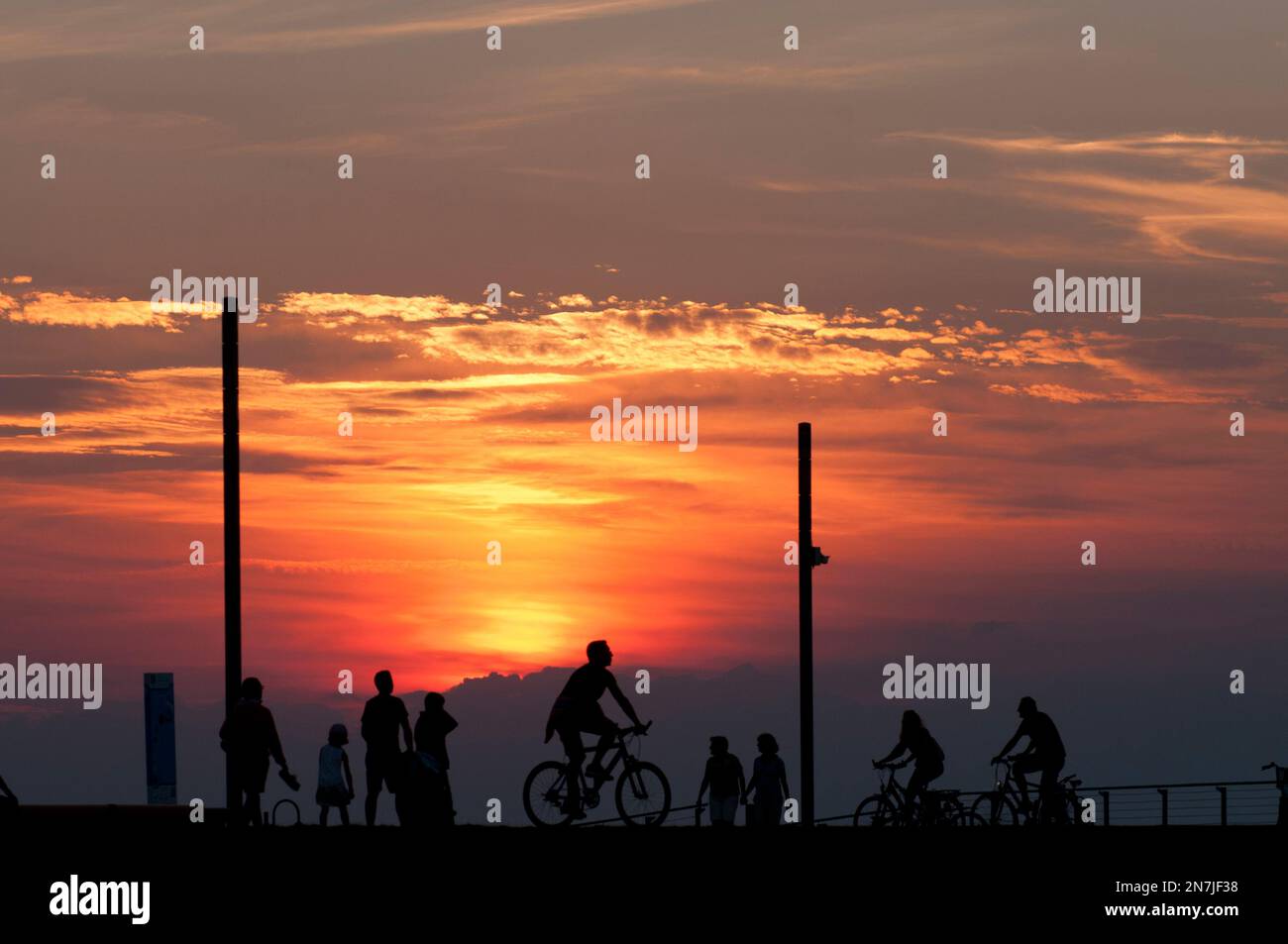 Le famiglie si trovano su una pista ciclabile presso la spiaggia di Heiligenhafen durante il tramonto. Foto Stock