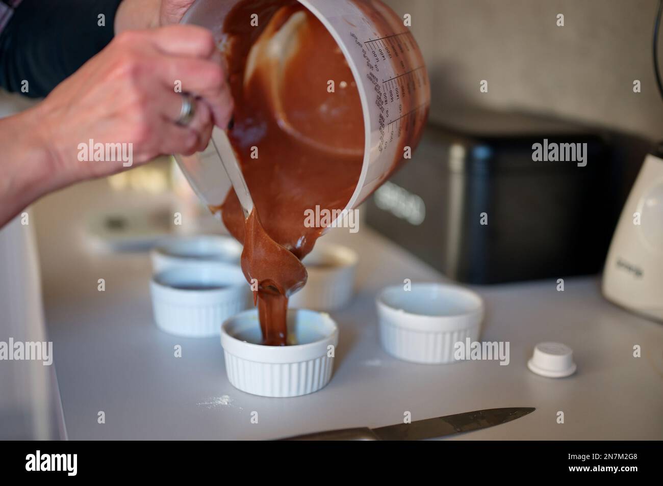 Le mani delle donne preparano la torta di lava al cioccolato Foto Stock