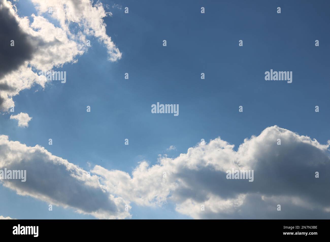 Nuvole e raggi di luce con un cielo blu brillante come sfondo creano un effetto celeste. Foto Stock