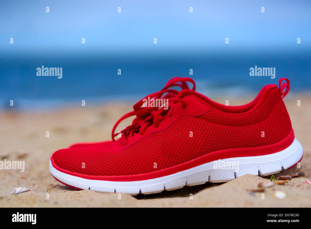 Scarpe rosse da donna su spiaggia di sabbia vuota. Calzature per lo sport e  il tempo libero sul mare. Primo piano Foto stock - Alamy