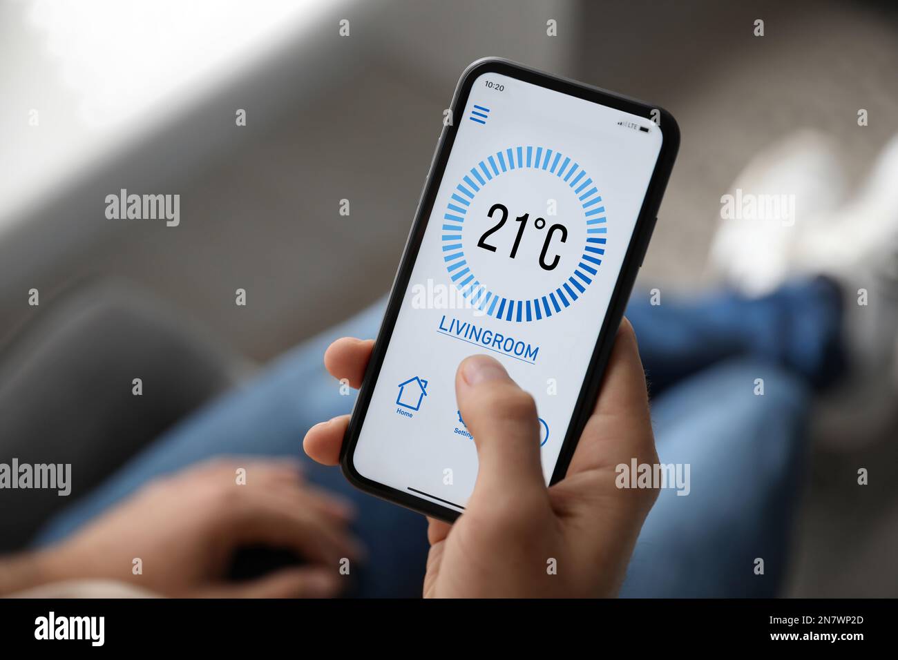 Uomo che utilizza lo smartphone per controllare l'impianto di riscaldamento in casa, in primo piano Foto Stock