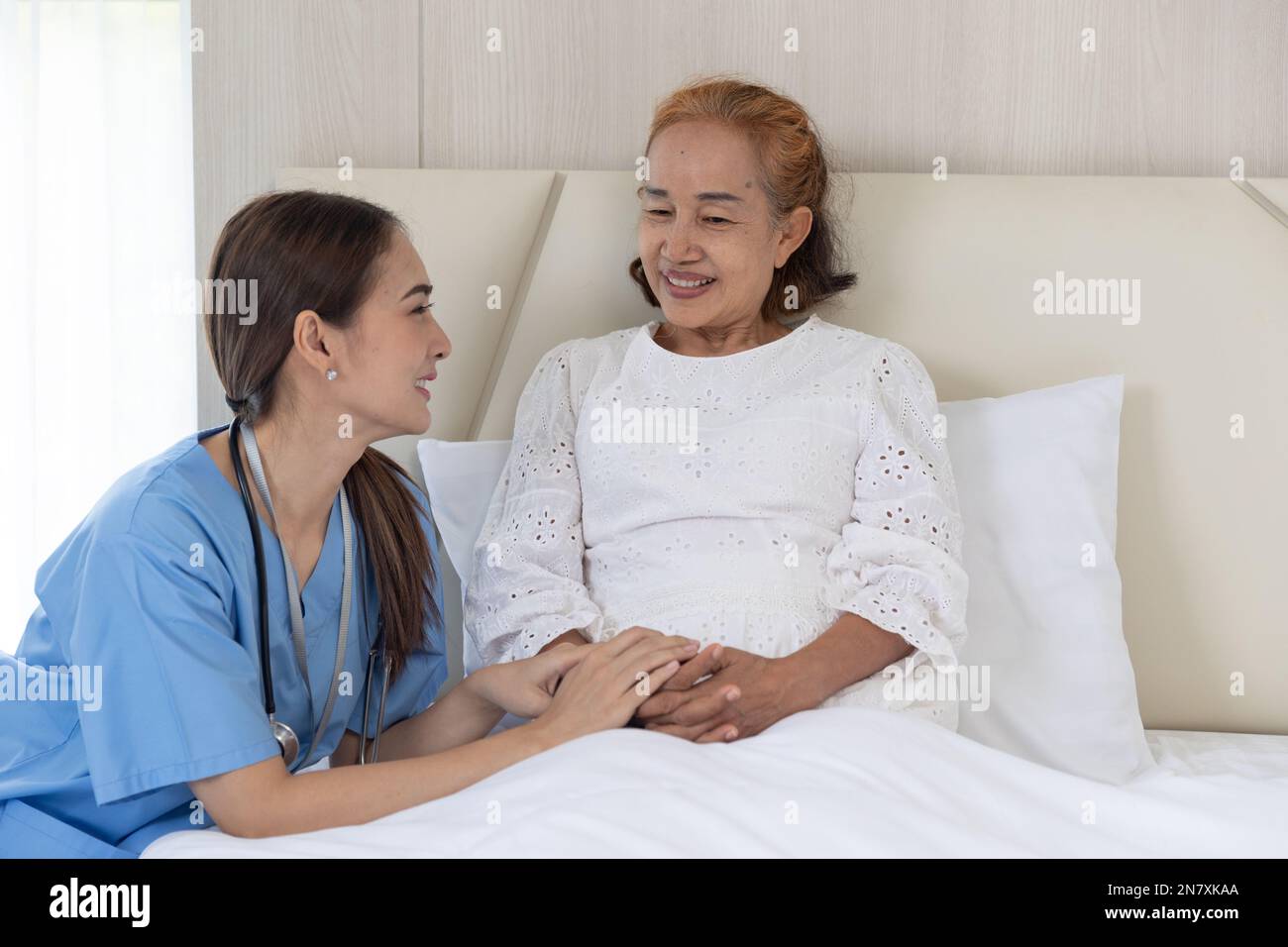 Infermiera cura paziente anziana donna anziana parlare di consolazione recupero a letto a casa Foto Stock