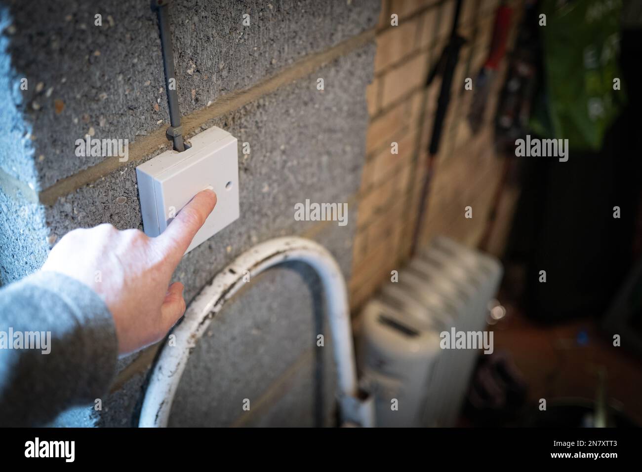 Messa a fuoco superficiale di una persona con il dito per spegnere un interruttore luci in un garage residenziale. Foto Stock