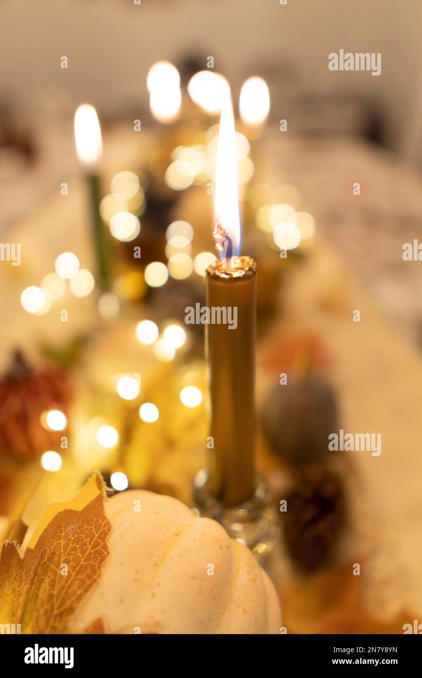 Uno scatto verticale di una candela illuminata con luci bokeh sullo sfondo sfocato per la cena del Ringraziamento Foto Stock