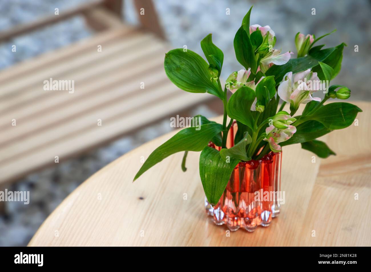 Un piccolo bouquet di fiori si trova in un vaso di vetro su un tavolo di legno. Alstroemeria, comunemente chiamata il giglio peruviano o giglio degli Inca Foto Stock