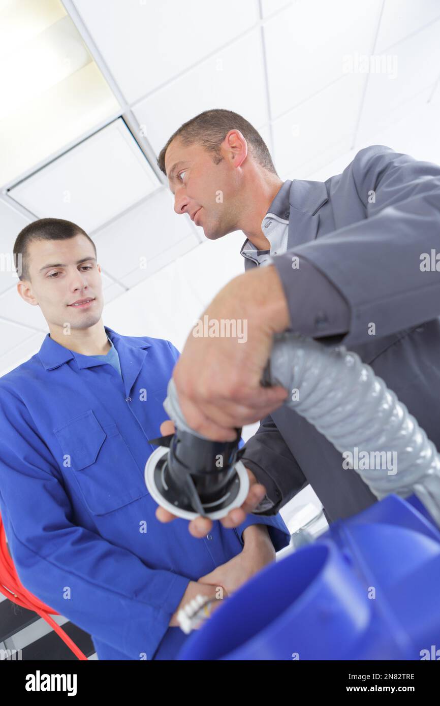 Il tecnico di manutenzione e controllo di apprendista di un tubo di ventilazione nella costruzione Foto Stock