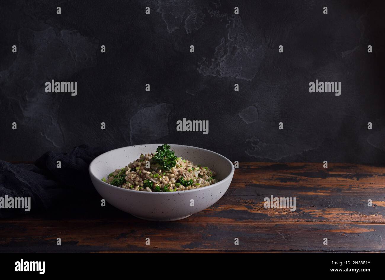 Grano saraceno verde sano con kale, aglio, cipolle verdi e semi, cibo disintossicante, superfood, cibo vegano su sfondo di legno scuro, spazio Foto Stock