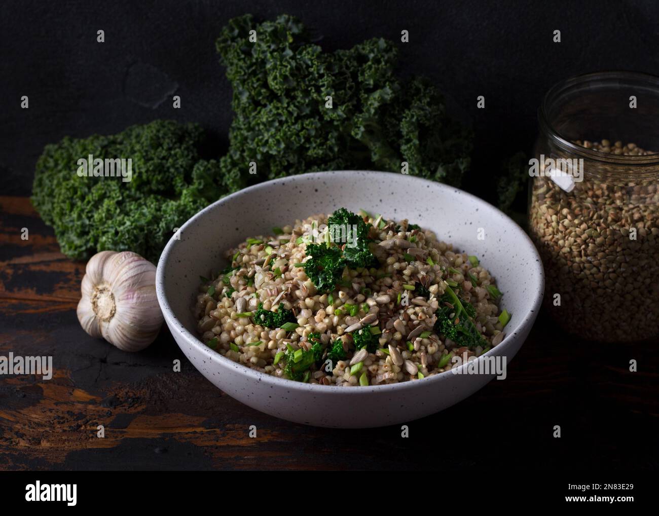 Grano saraceno verde sano con kale, aglio, cipolle verdi e semi, disintossicazione alimentare, superfood, vegan alimentare su sfondo di legno scuro Foto Stock