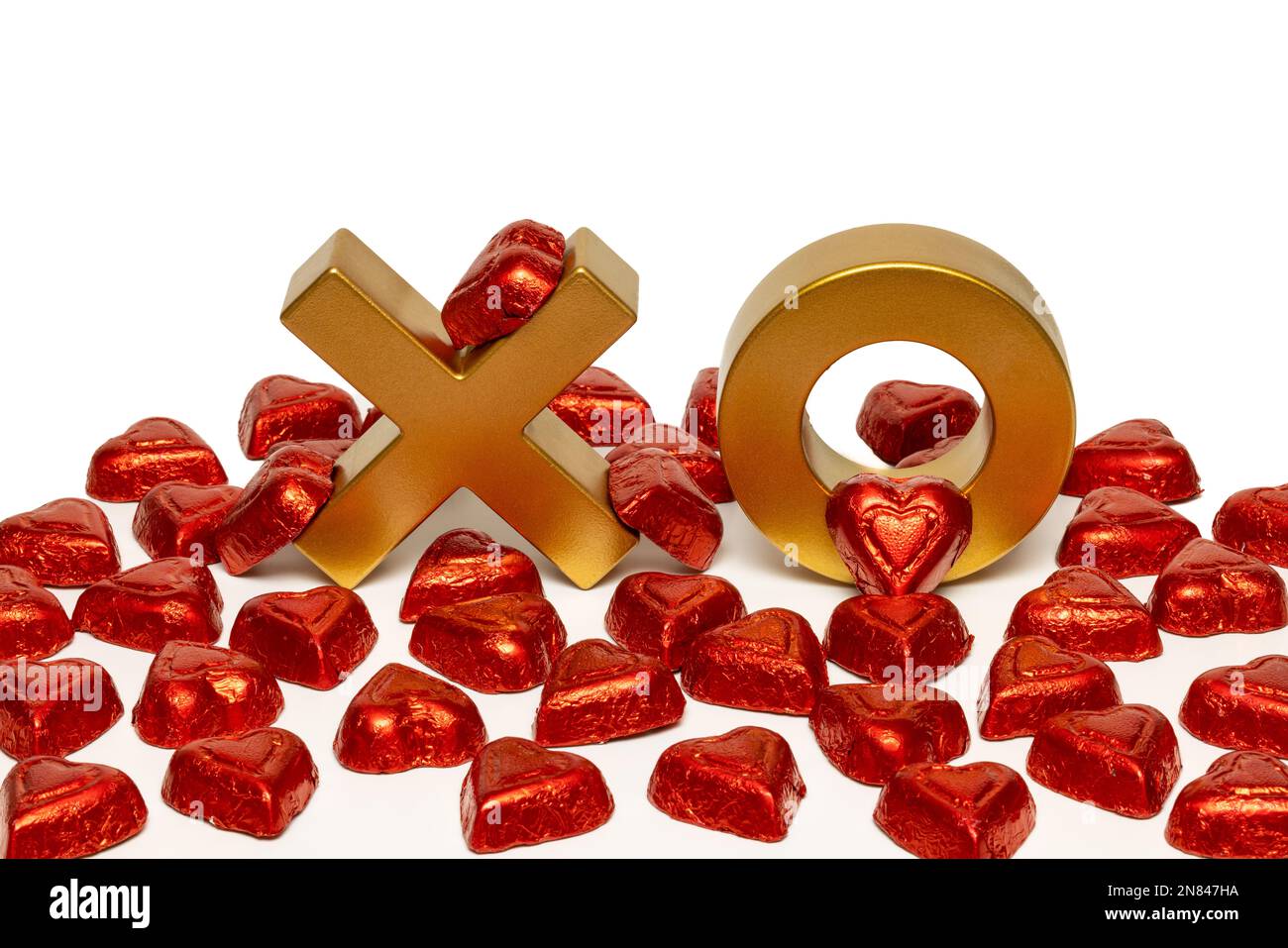 X e o con cuori di cioccolato in foglio rosso Foto Stock