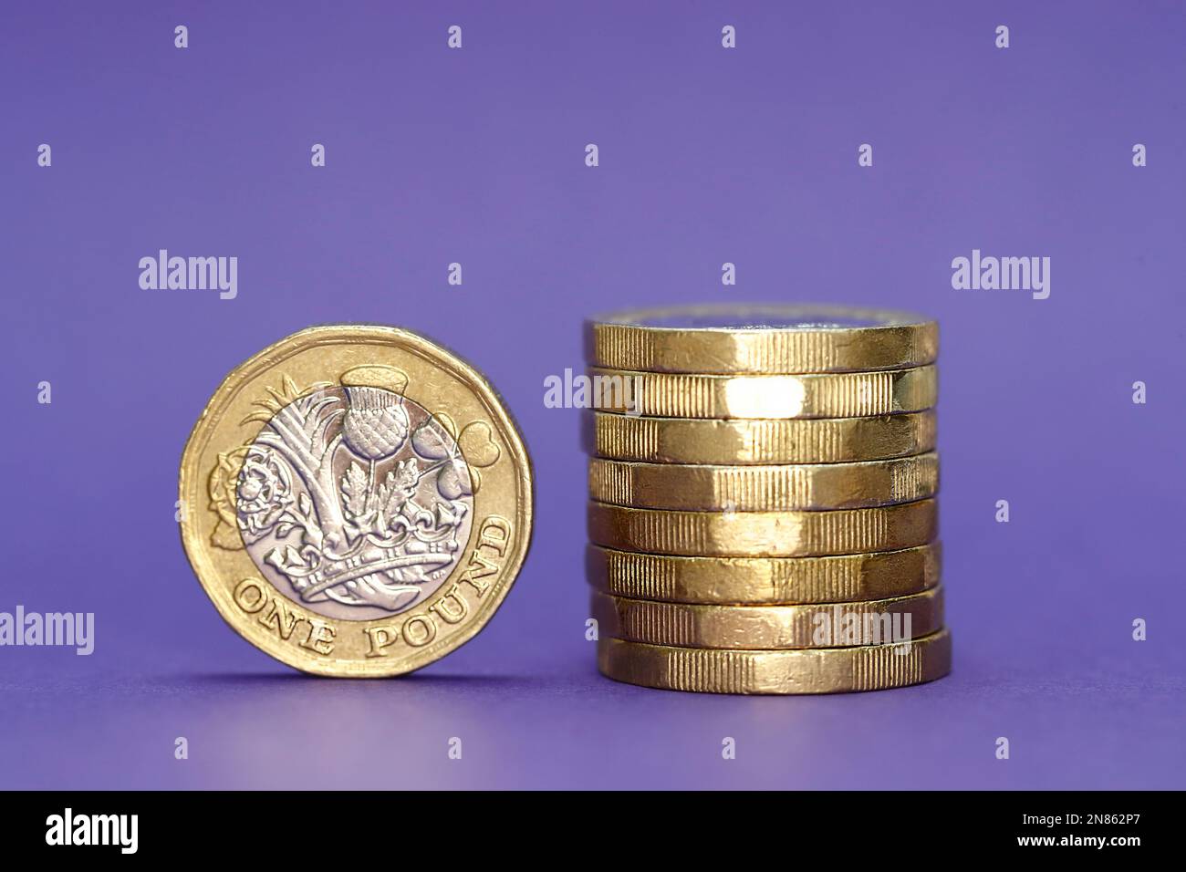 Monete della Sterlina Britannica una si è levata in piedi sul bordo e otto impilate sul lato destro Foto Stock