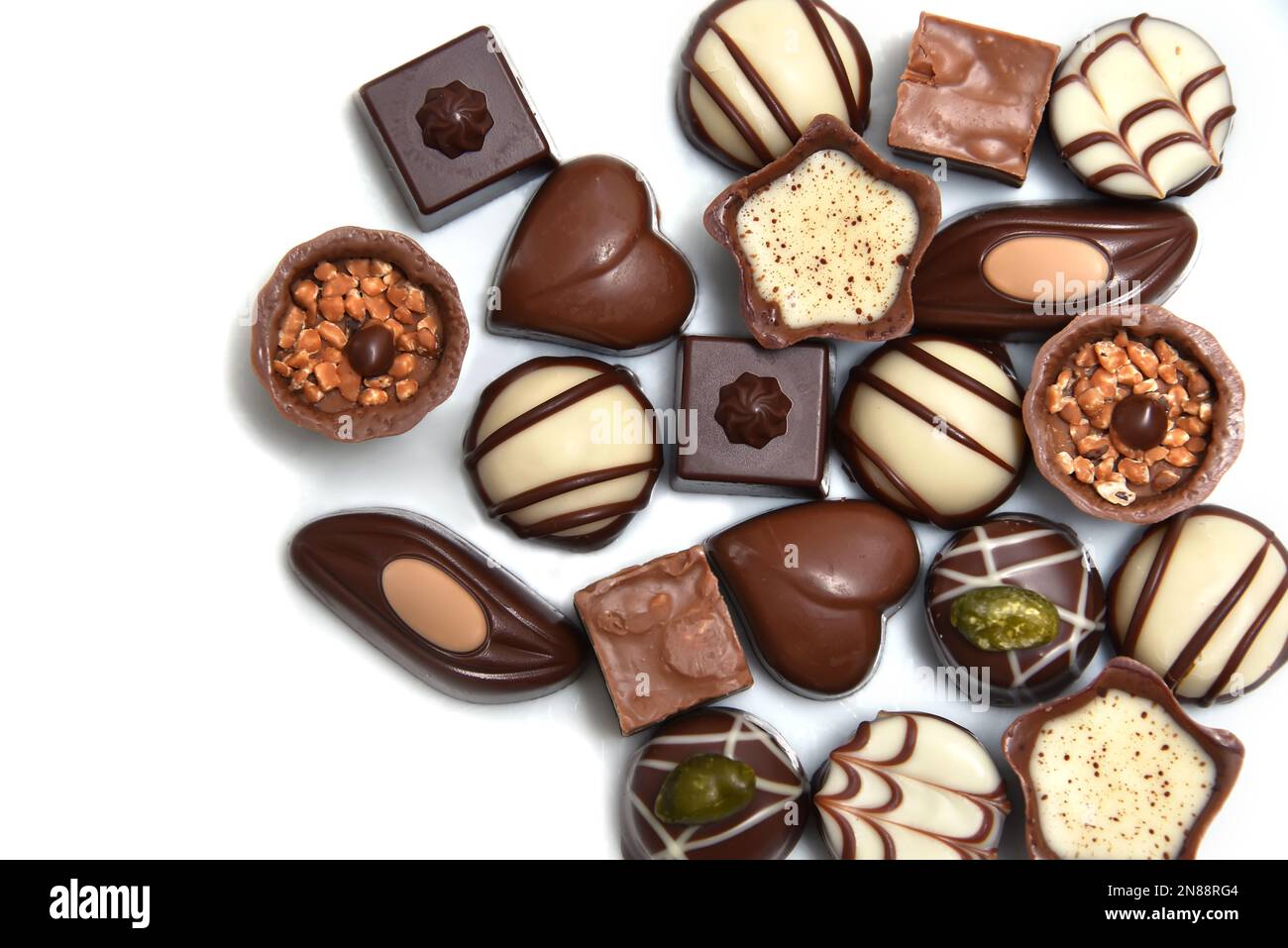 Primo piano di una selezione di cioccolatini di lusso, con una varietà di forme tra cui un cuore, fiorentine e pistacchi. Foto Stock
