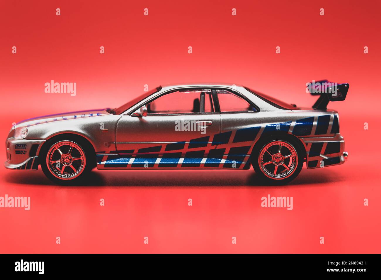 Autovettura FAST&Furious Nissan Skyline GT-R R34 1:43, vista laterale, sfondo rosso Foto Stock