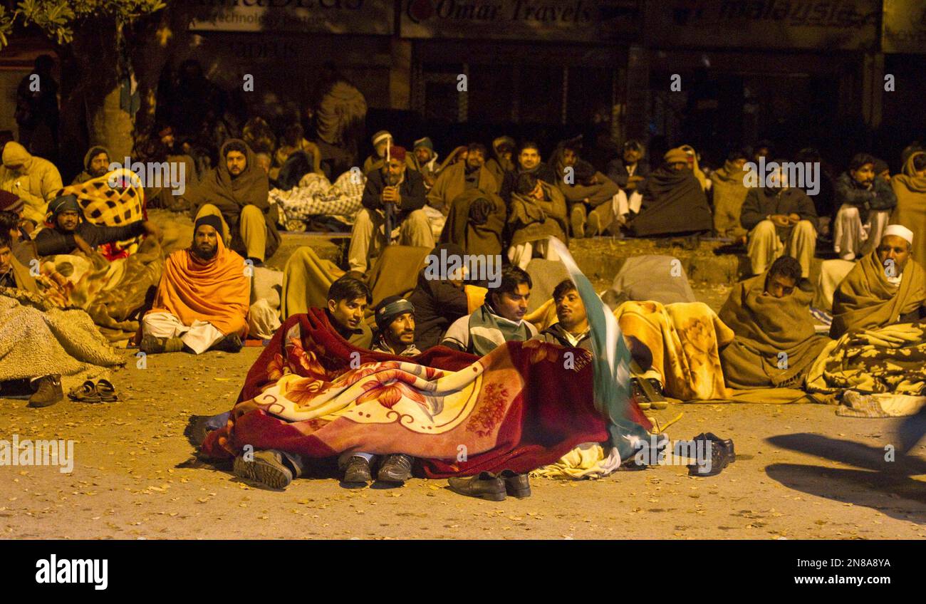 Supporters of Pakistani Sunni Muslim cleric Tahir-ul-Qadri, rest in a cold weather at an anti government rally in Islamabad, Pakistan Tuesday, Jan. 15, 2013. Thousands of Pakistanis fed up with political leaders they say are corrupt and indifferent rallied in the Pakistani capital Tuesday, as the fiery cleric who organized the rally called for the government to resign and for his followers to remain on the streets until then. (AP Photo/Anjum Naveed) Foto Stock