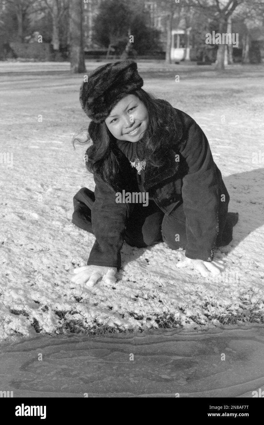 giovane donna sorridente immigrante del sud est asiatico gode il suo primo inverno britannico nel parco pubblico coperto di neve portsmouth inghilterra inverno 2002 2003 Foto Stock