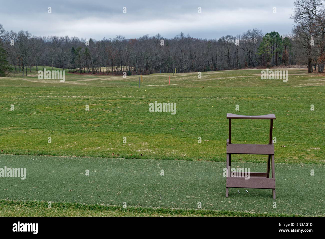 Campo di guida vuoto chiuso per la stagione in un campo da golf pieno di palle sparse sull'erba con pennarelli a distanza e un porta-borsa nel forgroun Foto Stock