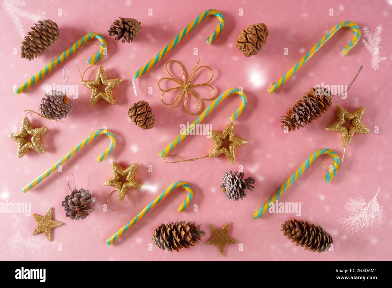 Festive ornamenti di Natale e decorazioni con canne caramelle, coni e giocattoli su sfondo di carta rosa, vista dall'alto, piatto. Foto Stock