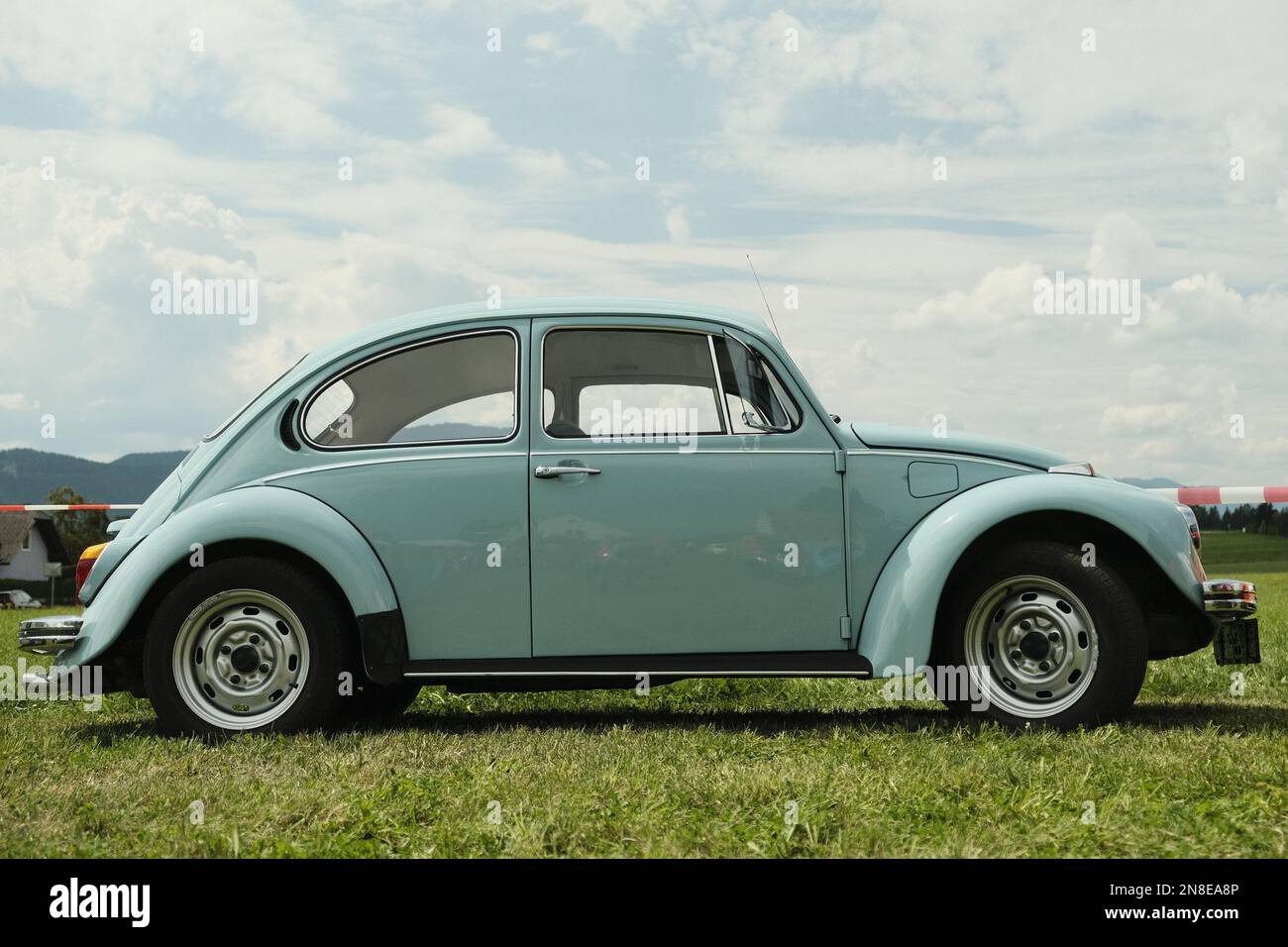 Un Beatle Volkswagen blu parcheggiato su erba con sfondo cielo blu e nuvoloso a Spielberg, Austria Foto Stock