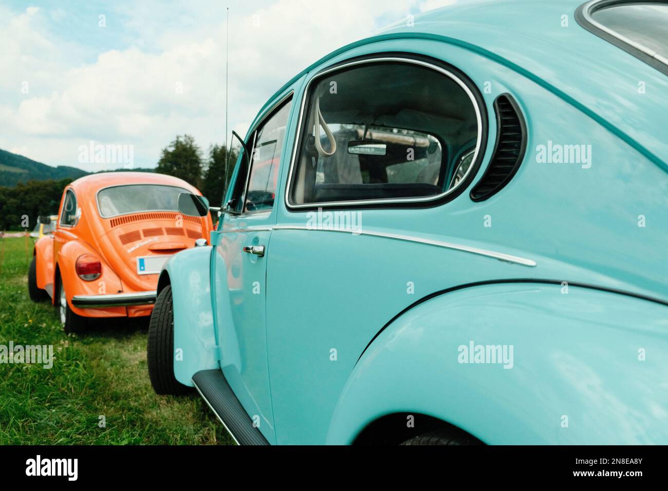 Una Volkswagen Beatle blu e arancione parcheggiata in erba a Spielberg, Austria Foto Stock