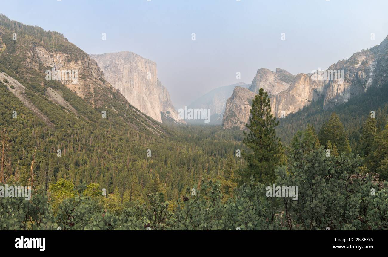 Vista panoramica del Tunnel View con qualche fumo tra le montagne, in Yosemite NP Foto Stock