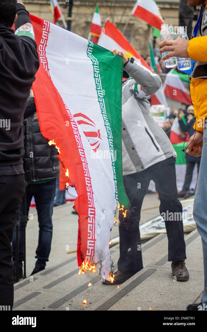 Londra, Regno Unito - 11 febbraio 2023: Manifestanti che bruciano la bandiera della Repubblica islamica dell'Iran come oggi segna il 44th° anniversario della Rivoluzione islamica in Iran. Oggi, dopo più di cinque mesi di continua protesta a sostegno della donna, della vita, del movimento per la libertà, migliaia di manifestanti si sono riuniti a Trafalgar Sq. Denunciare il regime in Iran. I manifestanti tenevano bandiera Shir-o-Khorshid (Leone e Sole) dell'Iran, la bandiera, o il suo emblema, facevano parte dell'identità nazionale iraniana per secoli, che fu cambiata dopo la Rivoluzione islamica del 1979. Credit: Sinai Noor/Alamy Live News Foto Stock