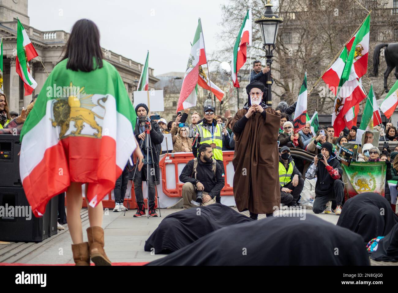 Londra, Regno Unito - 11 febbraio 2023: Esecuzione di una battaglia tra gli Ayatollah e una ragazza iraniana su hijab e libertà. Oggi ricorre il 44th° anniversario della Rivoluzione islamica in Iran. Dopo più di cinque mesi di continua protesta a sostegno della donna, della vita, del movimento per la libertà, migliaia di manifestanti si sono riuniti a Trafalgar Sq. Denunciare il regime in Iran. I manifestanti tenevano la bandiera Shir-o-Khorshid (Leone e Sole) dell'Iran. Questa bandiera è stata una parte dell'identità nazionale iraniana per secoli, che è stata cambiata dopo la Rivoluzione islamica nel 1979. Credit: Sinai Noor/Alamy Live News Foto Stock