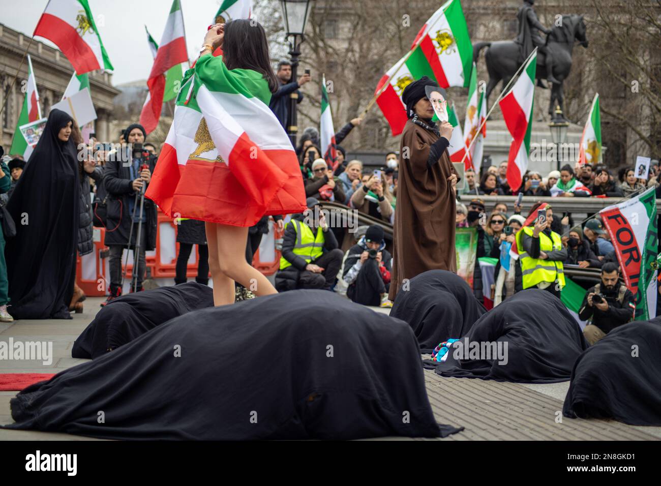Londra, Regno Unito - 11 febbraio 2023: Esecuzione di una battaglia tra gli Ayatollah e una ragazza iraniana su hijab e libertà. Oggi ricorre il 44th° anniversario della Rivoluzione islamica in Iran. Dopo più di cinque mesi di continua protesta a sostegno della donna, della vita, del movimento per la libertà, migliaia di manifestanti si sono riuniti a Trafalgar Sq. Denunciare il regime in Iran. I manifestanti tenevano la bandiera Shir-o-Khorshid (Leone e Sole) dell'Iran. Questa bandiera è stata una parte dell'identità nazionale iraniana per secoli, che è stata cambiata dopo la Rivoluzione islamica nel 1979. Credit: Sinai Noor/Alamy Live News Foto Stock