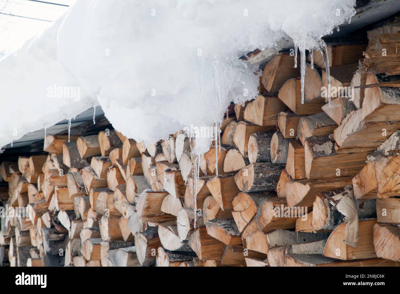 Legno tagliato e immagazzinato per l'inverno fuori sotto un tetto innevato, Jarrier, Maurienne, Savoia, Francia Foto Stock