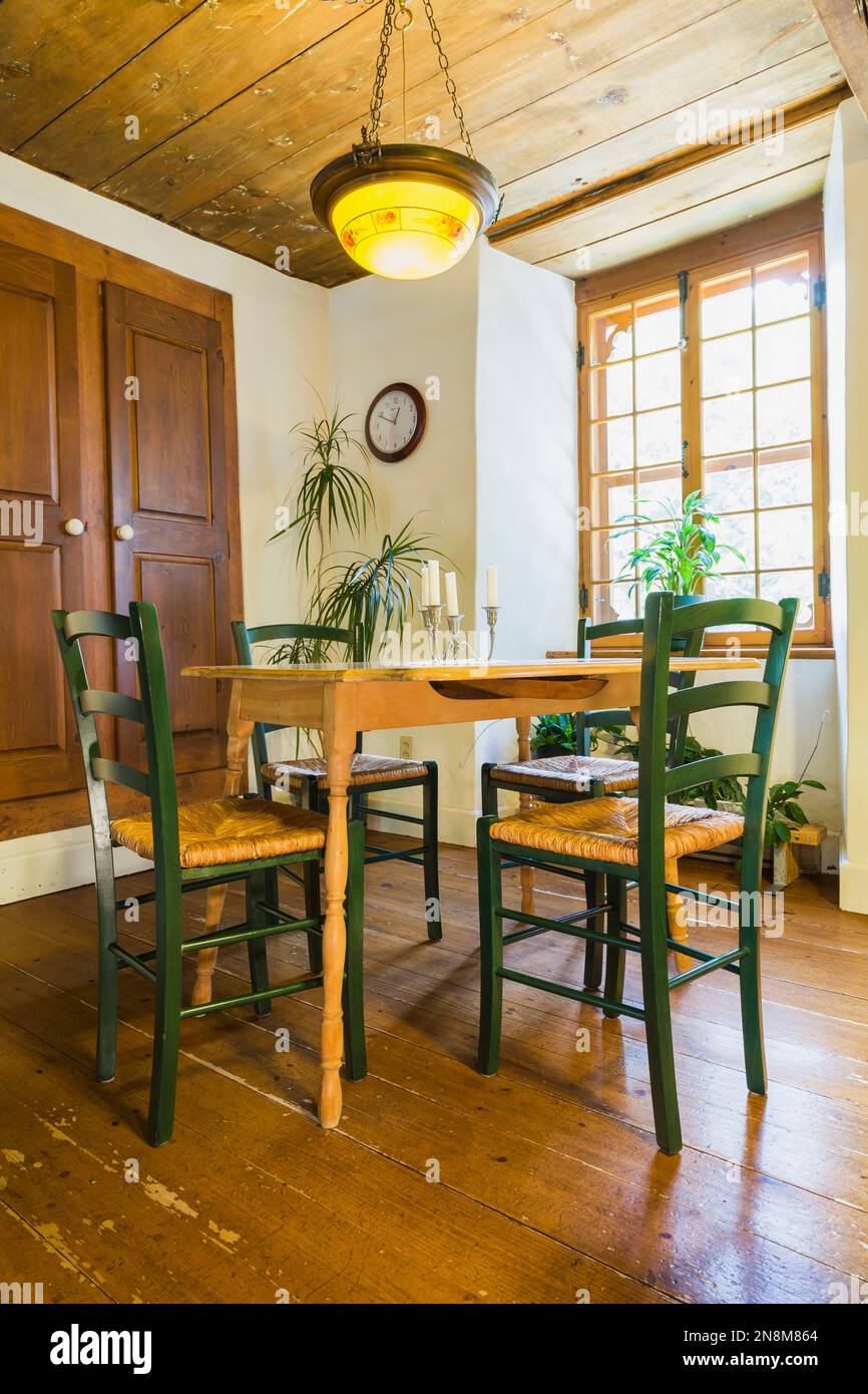 Tavolo da colazione in legno con sedie a sedere in canapa intrecciata verde all'interno di una vecchia casa in stile cottage risalente al 1760 circa. Foto Stock