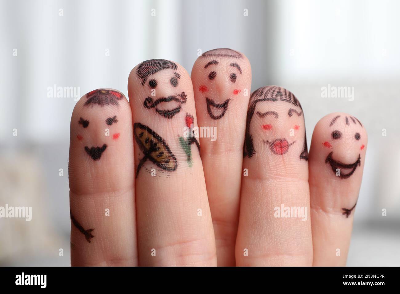 Cinque dita con disegni di volti felici su sfondo sfocato Foto Stock