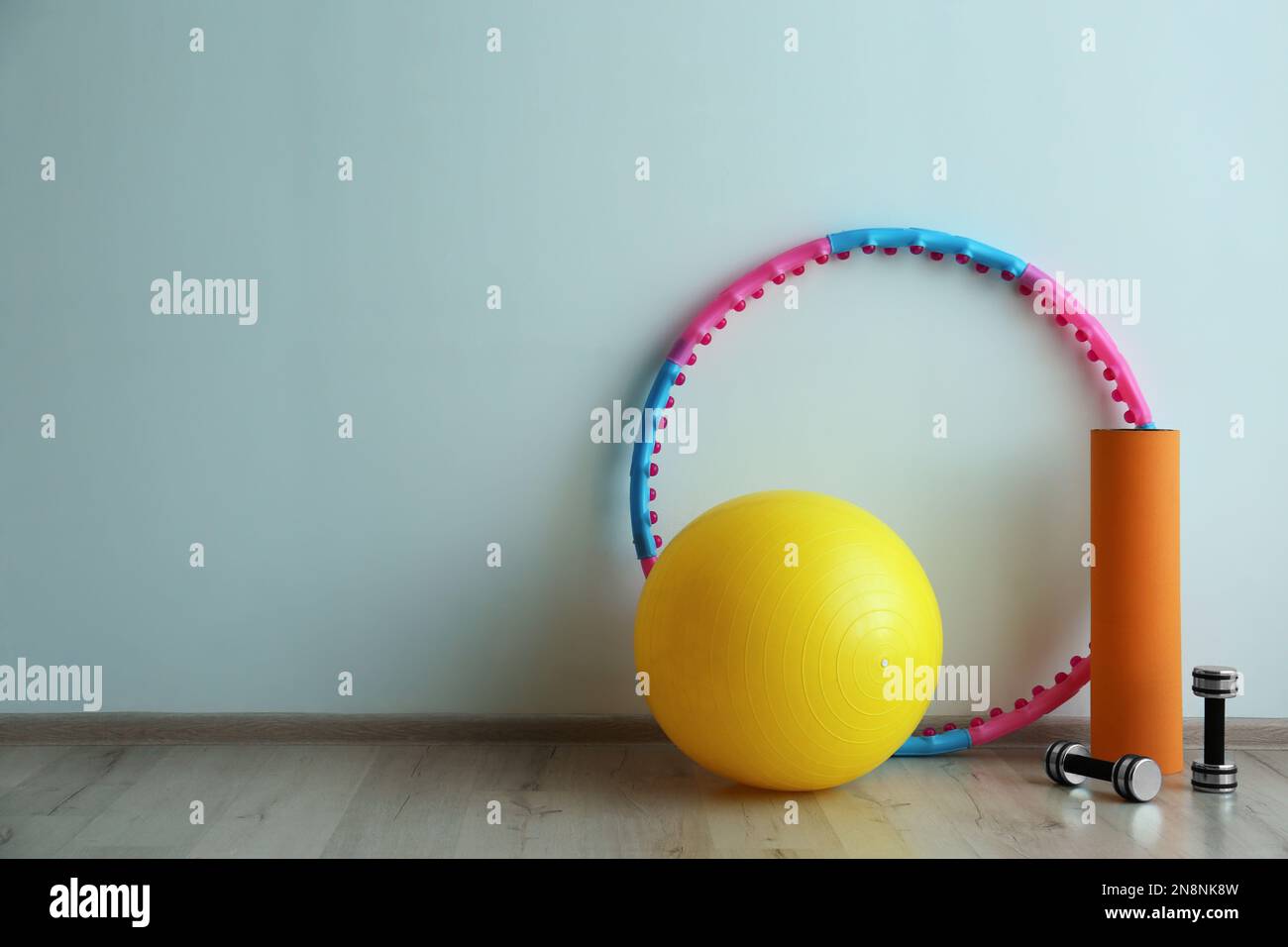 Hula Hoop, palla fitness, tappeto e manubri vicino alla parete di luce in  palestra. Spazio per il testo Foto stock - Alamy