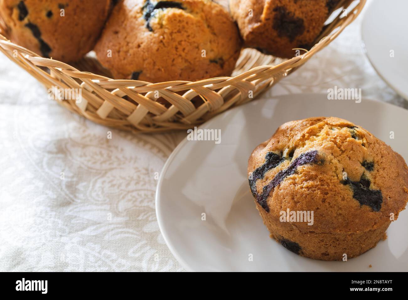 Muffin ai mirtilli appena sfornati nel cestino e nel piatto davanti con spazio per il testo Foto Stock