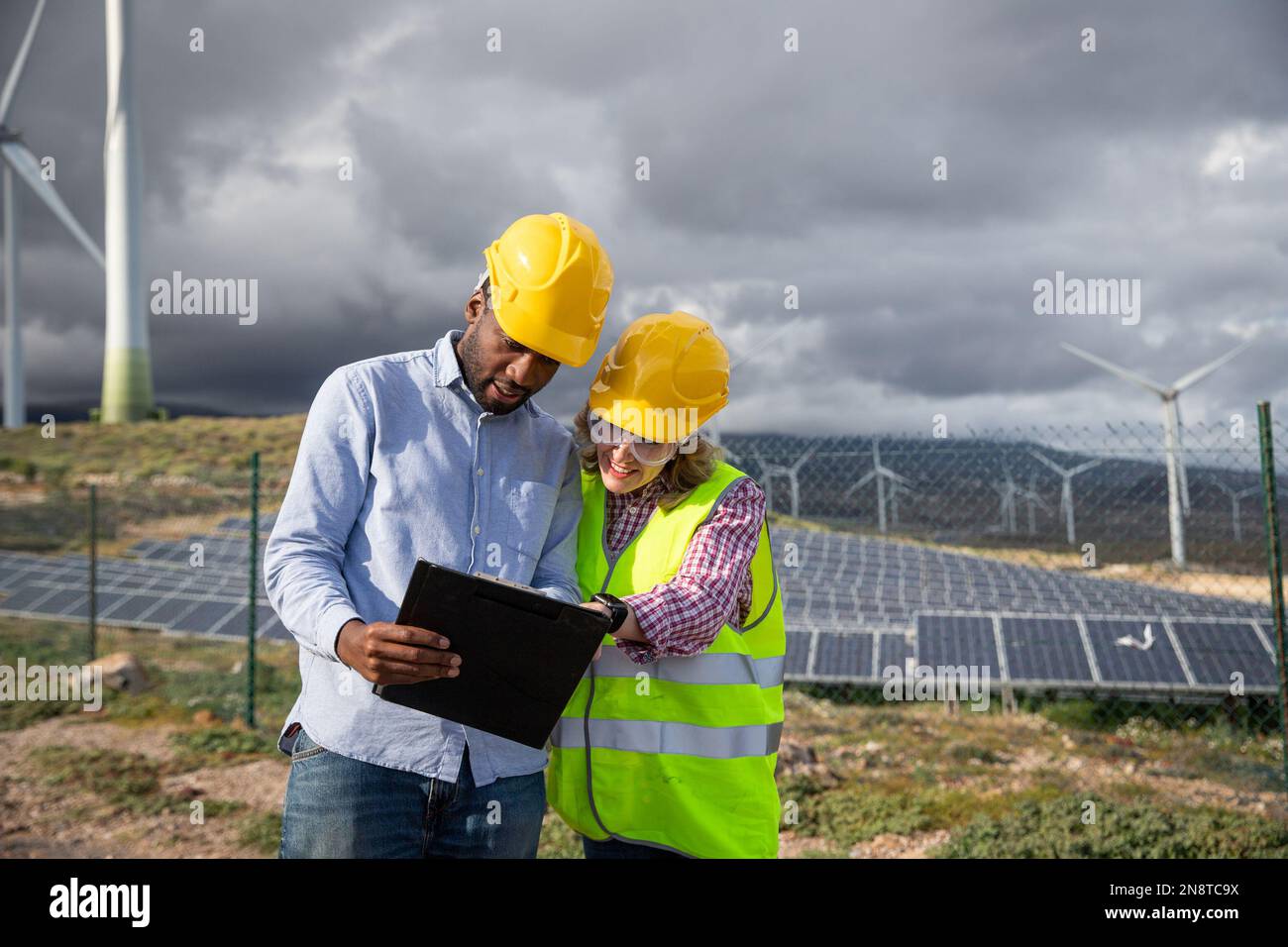 Due colleghi consultano i documenti mentre si trovano in una centrale fotovoltaica. Foto Stock Due colleghi consultano i documenti mentre si trovano in una centrale fotovoltaica. Foto Stock