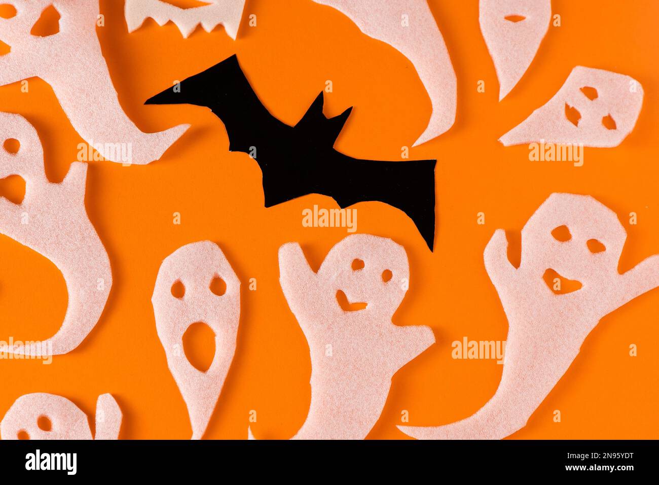 Fantasmi bianchi e mazza per la festa di Halloween. Immagine fantasma della carta di avvolgimento su sfondo arancione vista dall'alto. Fumetto Creepy Whisper. Fai-da-te fatto a mano. Impostare i caratteri boo. Foto Stock