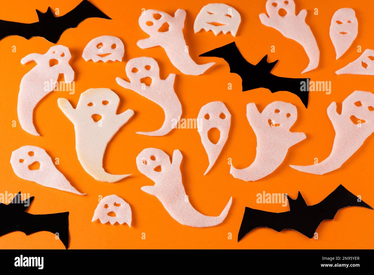 Fantasmi bianchi e mazza per la festa di Halloween. Immagine fantasma della carta di avvolgimento su sfondo arancione vista dall'alto. Fumetto Creepy Whisper. Fai-da-te fatto a mano. Impostare i caratteri boo. Foto Stock