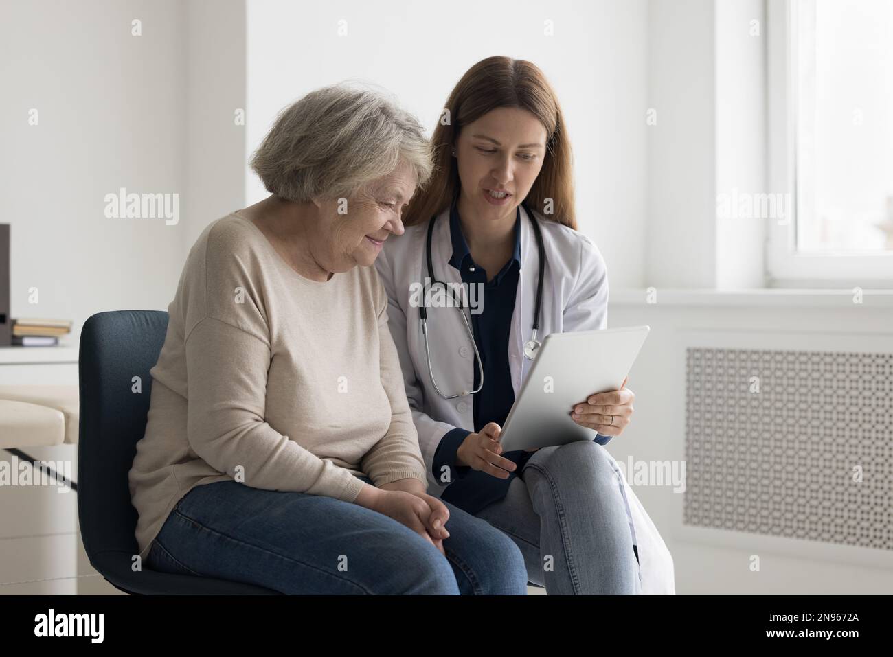 Medico geriatrico impegnato positivo che mostra il risultato del controllo medico sulla compressa Foto Stock