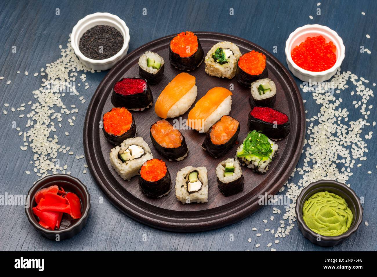 Diversi tipi di sushi su tavola rotonda. Il riso è sparso sulla tabella.  Condimenti in ciotole. Vista dall'alto. Sfondo blu Foto stock - Alamy